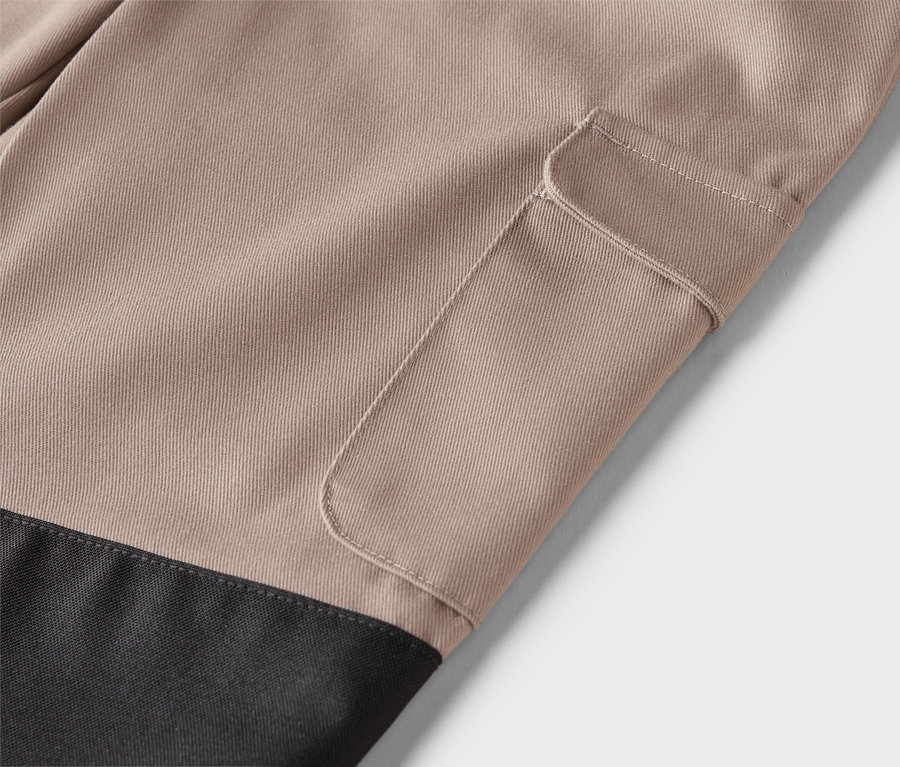 Nahaufnahme einer beigen Hose mit einer aufgesetzten Tasche und einem schwarzen unteren Teil.