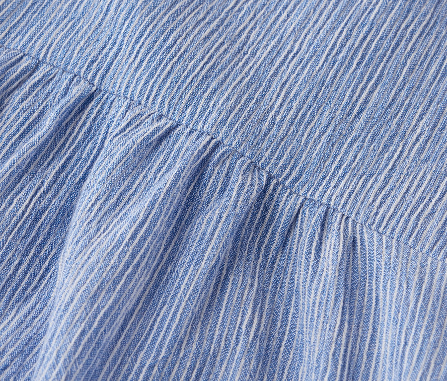 Nahaufnahme eines blau-weiß gestreiften Stoffes mit gerafften Details.