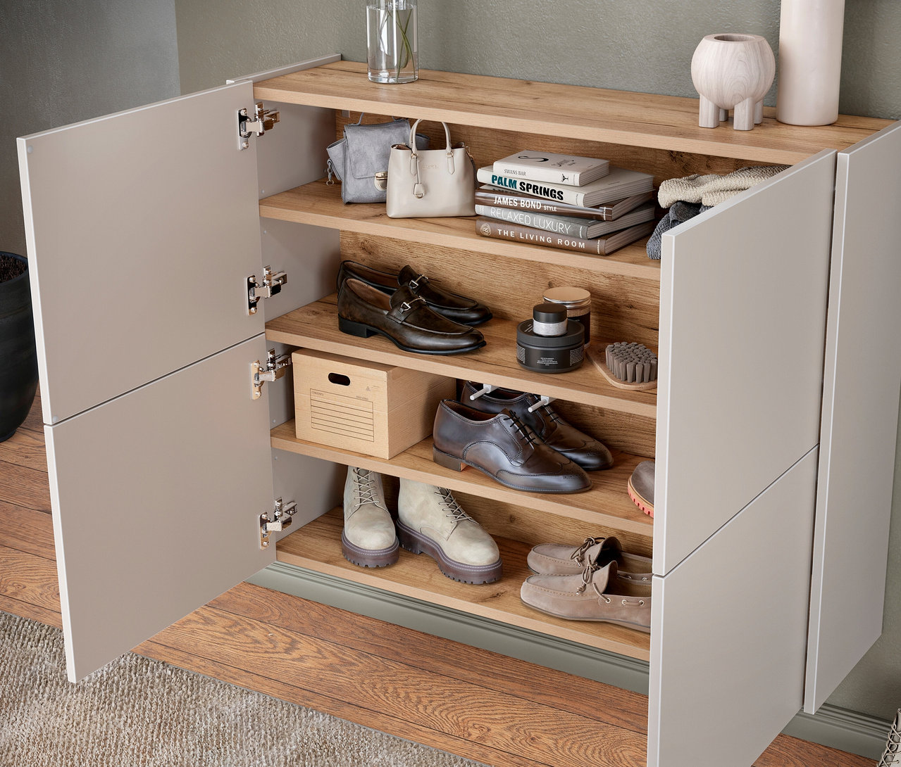 Offener Holzschuhschrank mit grauen Schuhen, Handtaschen und Pflegeprodukten.