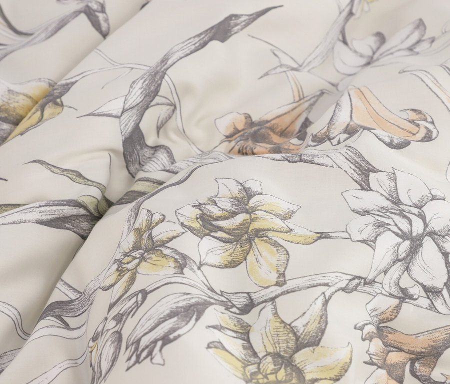 Heller Stoff mit floralem Muster in Grau, Gelb und Orange, weich gefaltet.