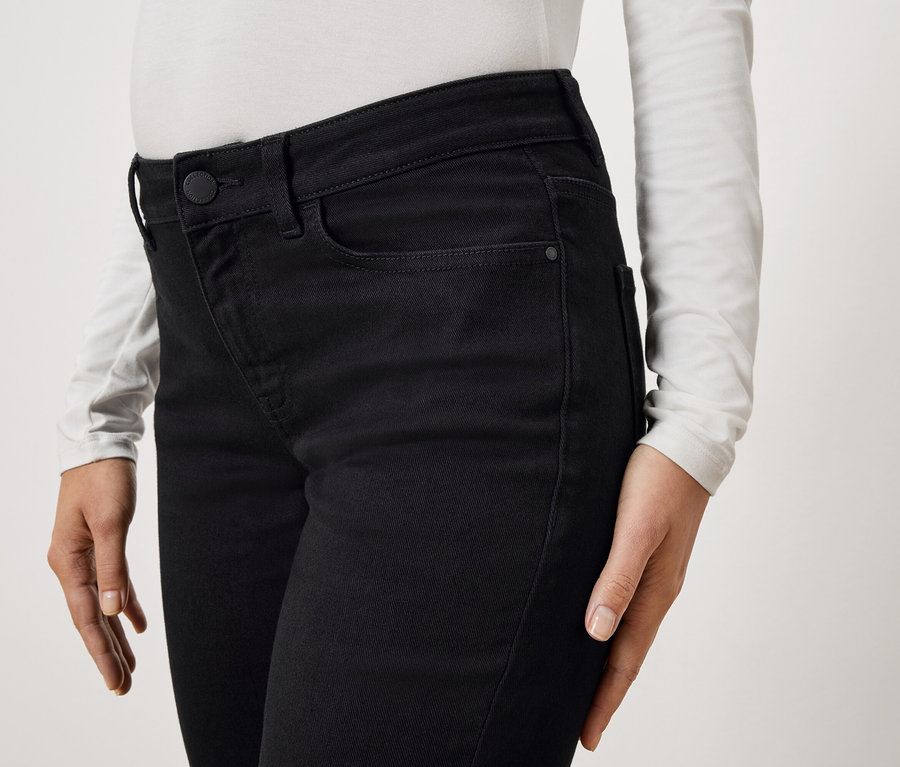 Nahaufnahme einer Person, die eine schwarze Jeans und ein langärmliges weißes Oberteil trägt.