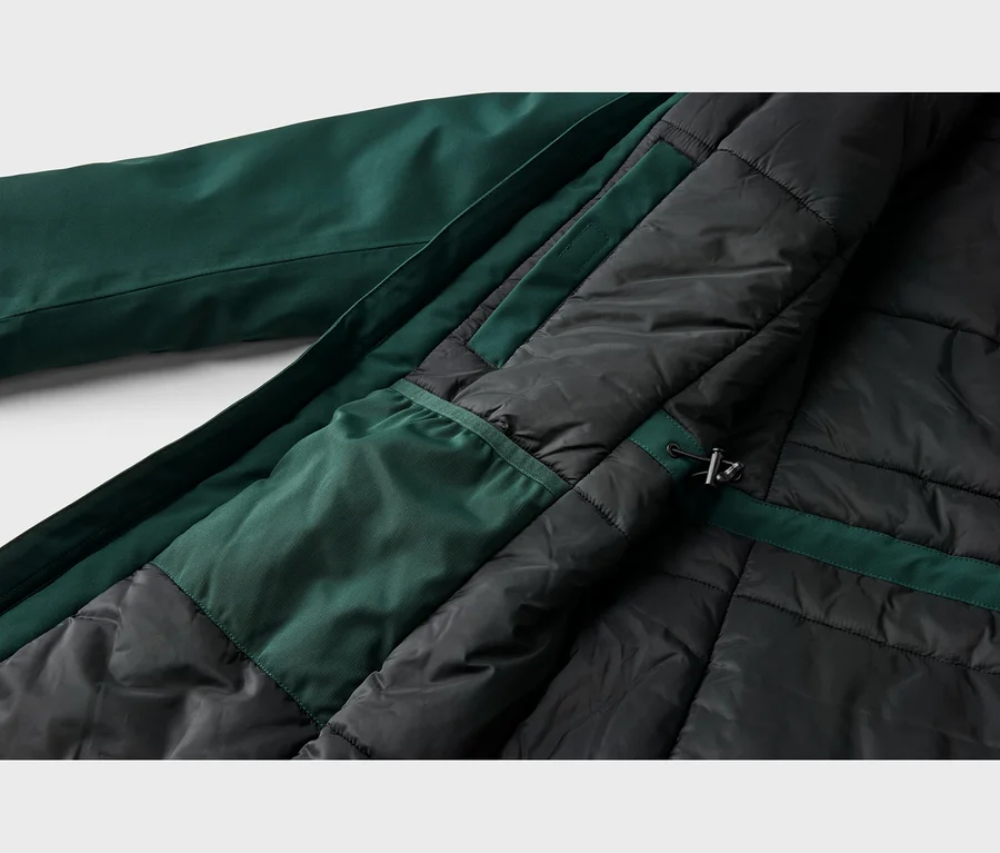 Nahaufnahme der Innenseite einer dunkelgrünen Jacke, die ihr schwarzes gestepptes Futter, eine innere dunkelgrüne Tasche und einen Kordelzug mit Stopper zeigt.
