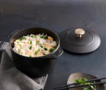 Gefüllte, schwarze, runde STAUB Reis-Cocotte, 16 cm, mit Deckel auf einem Tisch.