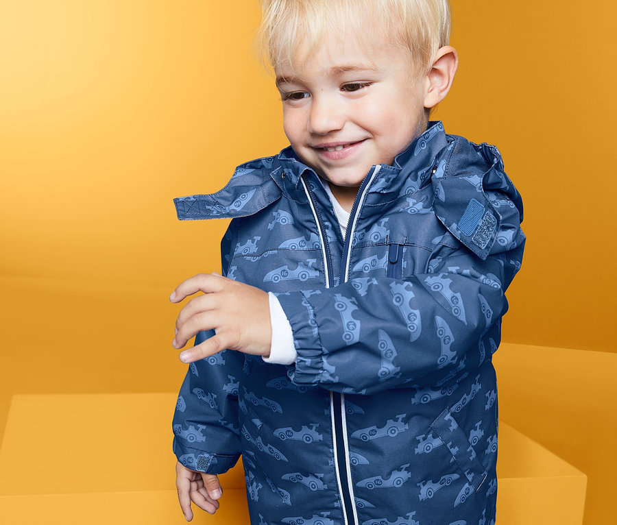 Ein Junge trägt eine blaue Regenjacke.