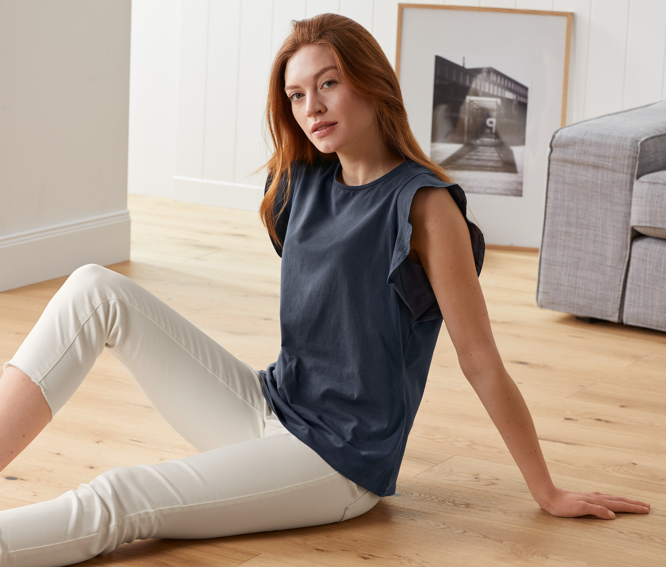 Frau sitzt auf dem Boden und trägt ein dunkelblaues EarthColors®-Top und eine weiße Hose.