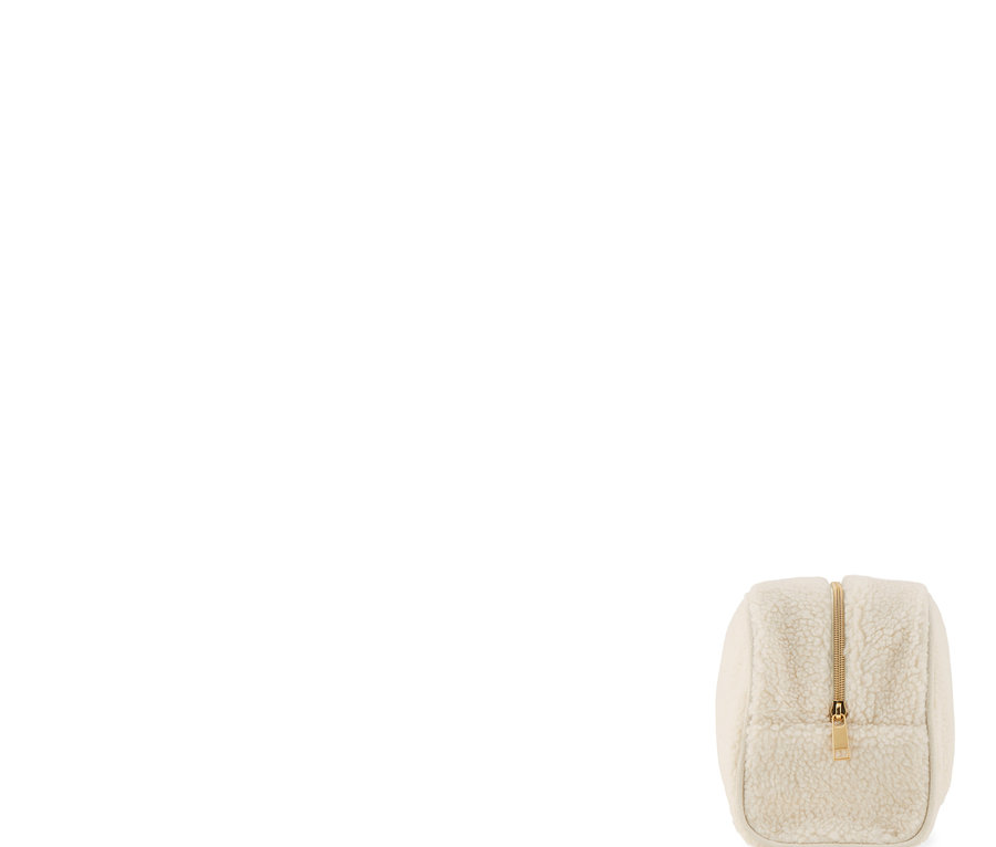 Eine Kulturtasche aus Teddyfell mit goldenem Reißverschluss.