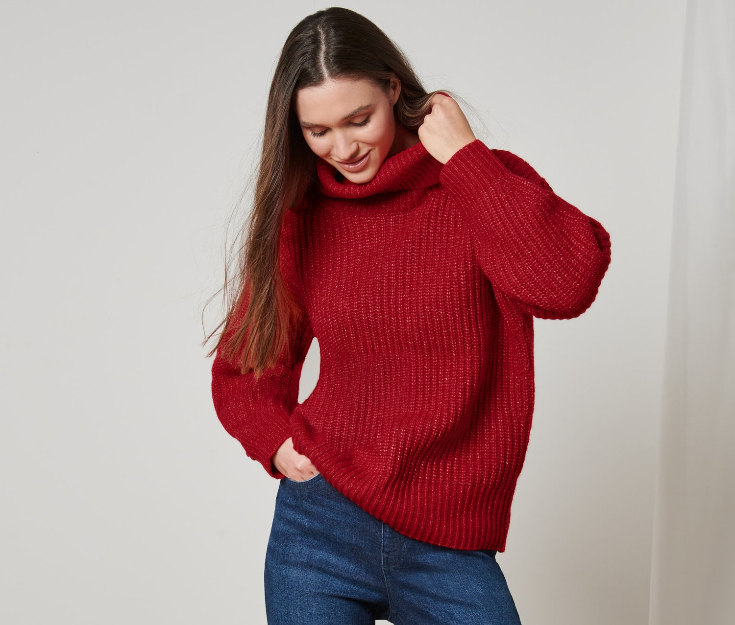 Frau trägt einen Grobstrick-Pullover mit Rollkragen und Jeans.