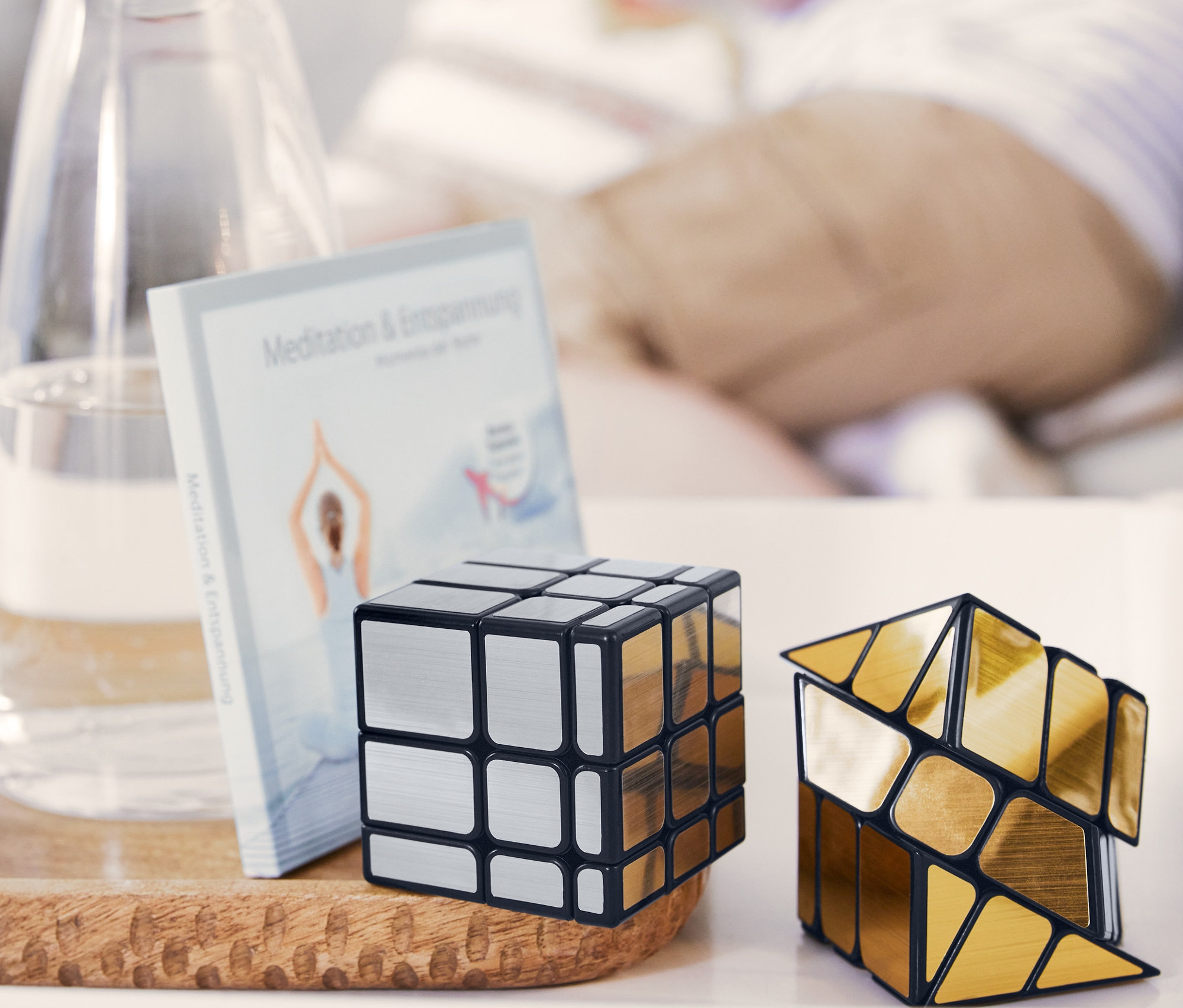 Zwei IQ-Würfel liegen auf einem Holztablett neben Wassergläsern.