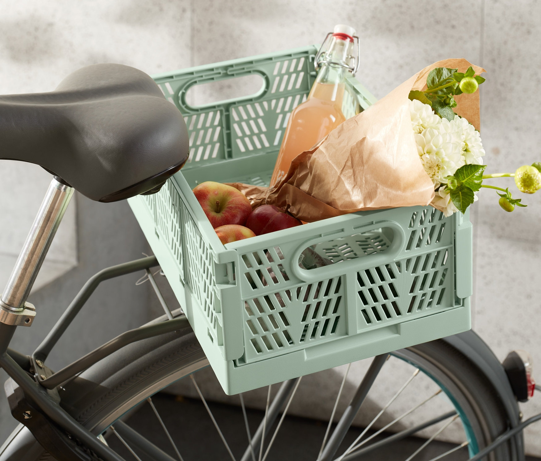 Urbane Fahrradkiste, klappbar mit Äpfeln, Blumen und einer Flasche auf einem Fahrrad.
