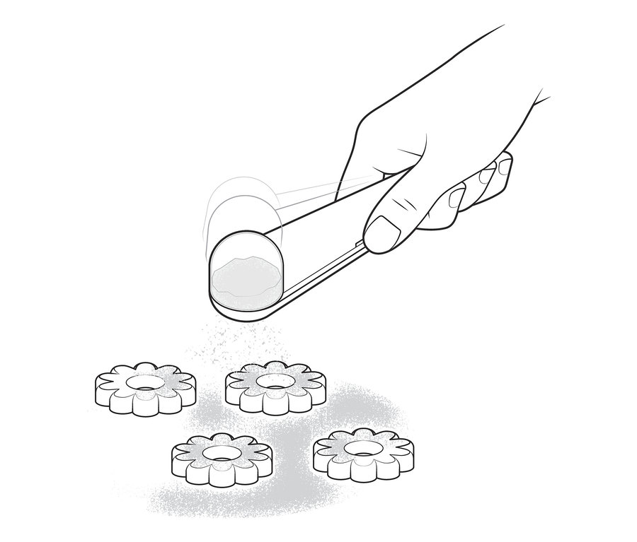 Eine Hand bestreut Kekse mit einem Puderzuckerstreuer mit Puderzucker.