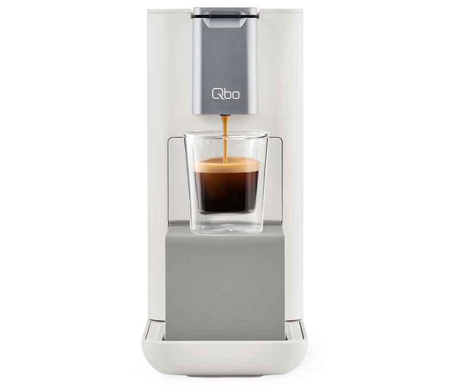 Kaffee wird aus einer Qbo ESSENTIAL Bright Sand Kaffeemaschine in ein Glas gegossen.