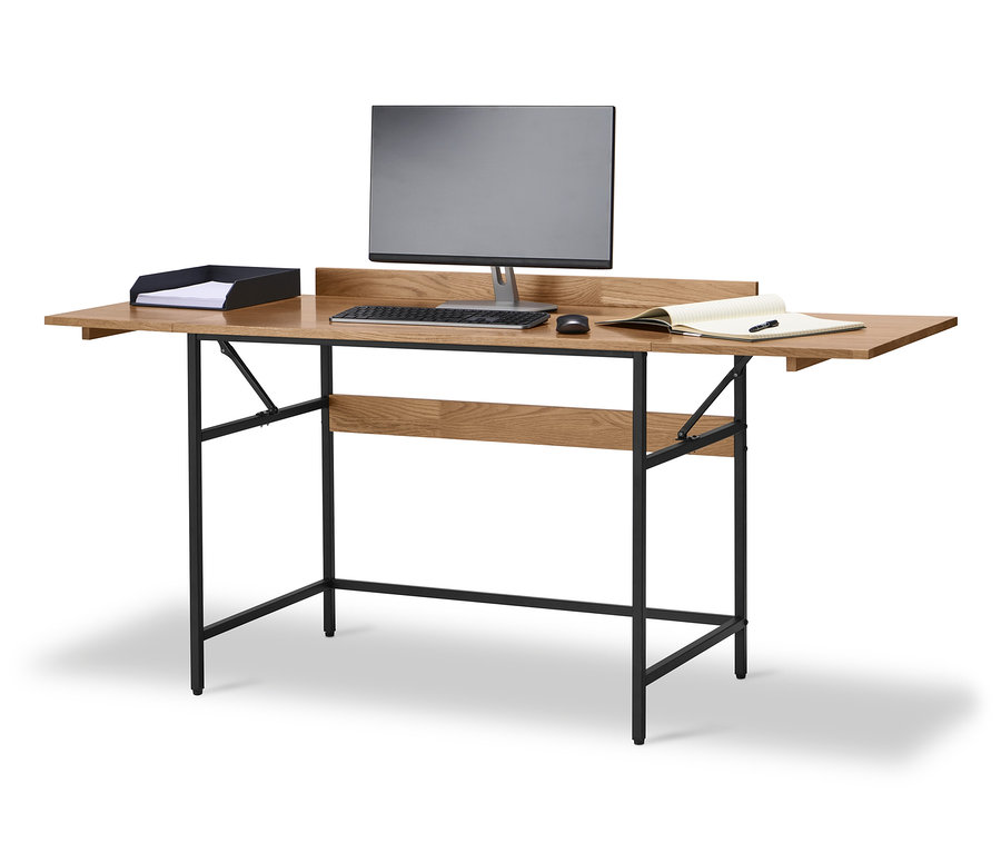 Erweiterbarer Schreibtisch aus Massivholz mit Monitor, Tastatur, Maus, Papierablage und Notizbuch auf der Tischplatte.