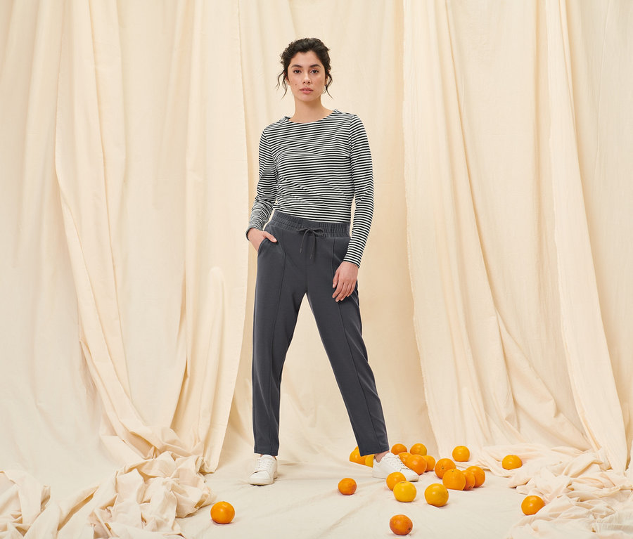 Frau posiert in Joggpants mit Biese und einem gestreiften Langarmshirt, schwarz.