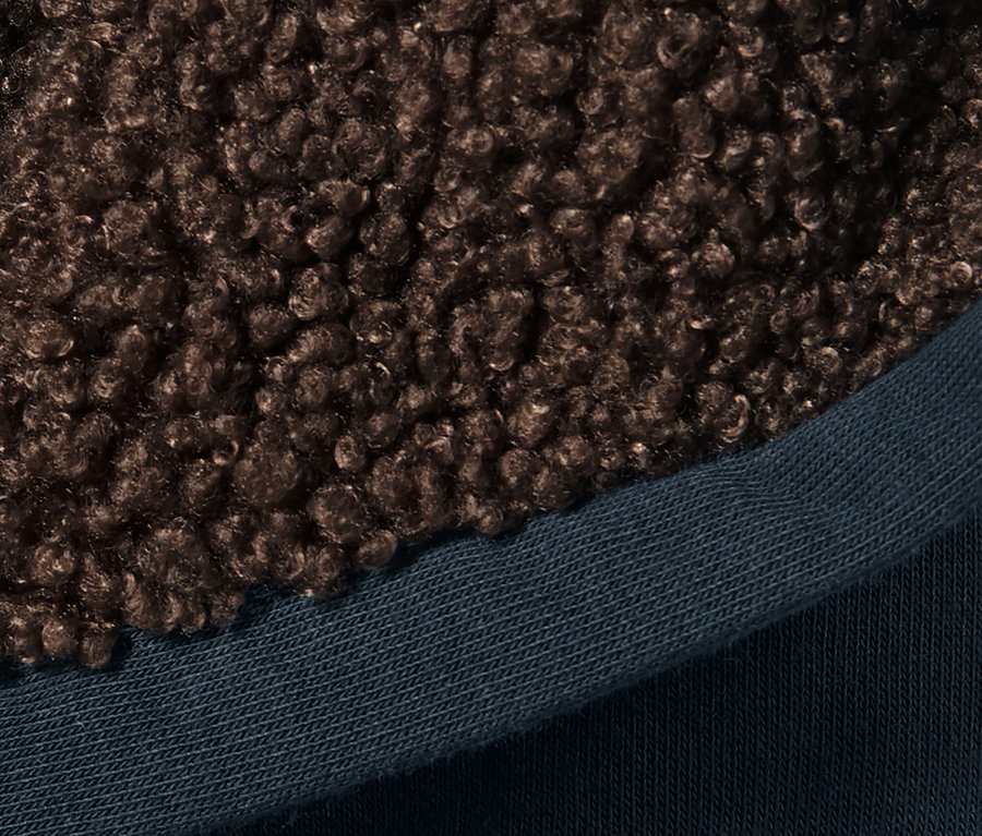 Detail einer Kinder-Sweat-Jacke mit brauner Fellkapuze und blauem Saum.