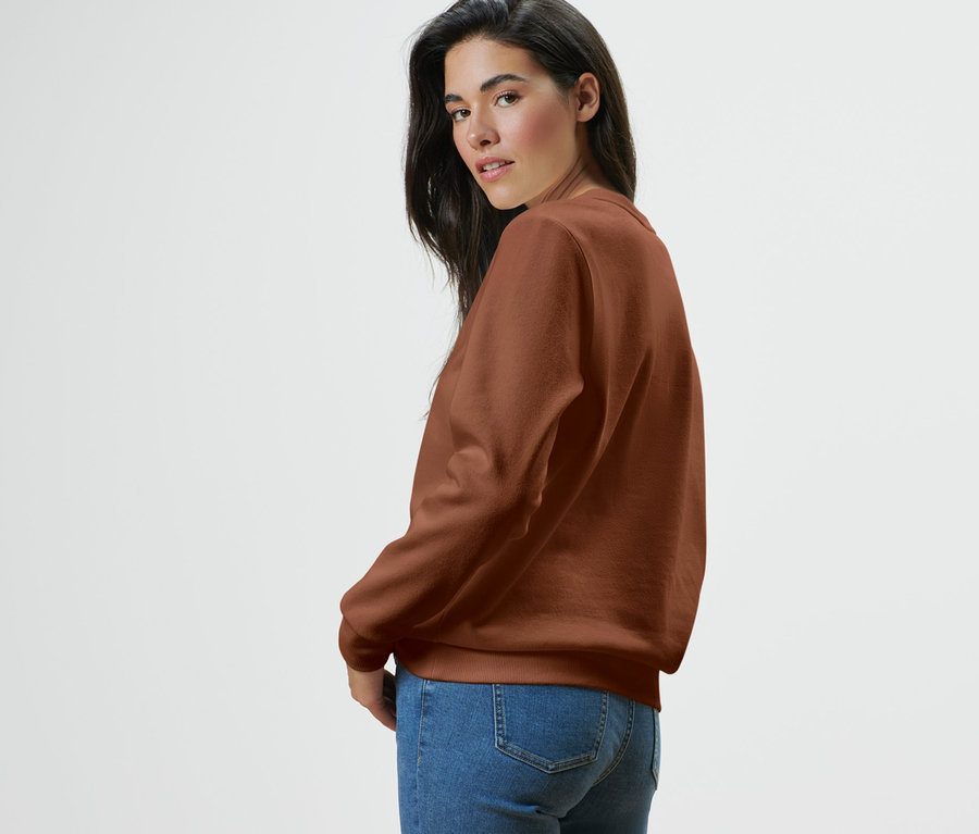 Frau blickt über die Schulter und trägt ein Sweatshirt und Jeans.