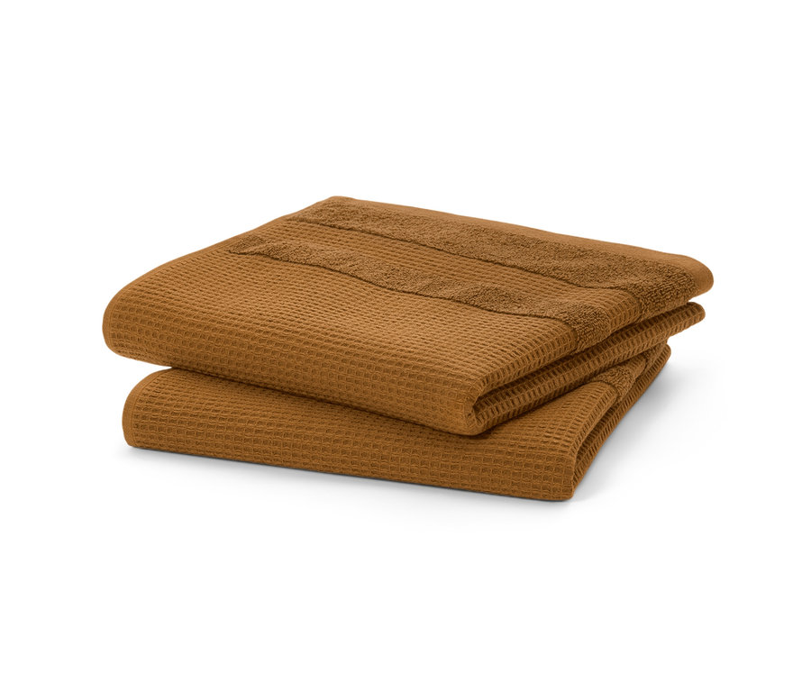 Zwei ockerfarbene Premium-Waffelpiqué-Handtücher liegen gefaltet übereinander.