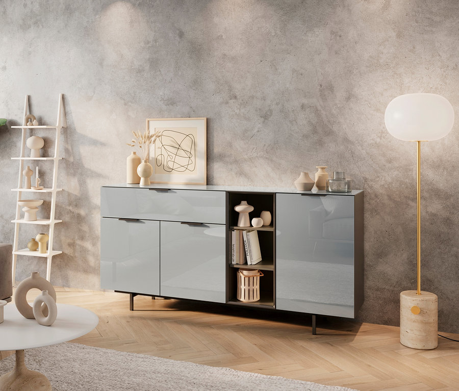 Ein Wohnzimmer mit einem grauen Sofa, einem weißen Couchtisch und einem Sideboard aus Glas.