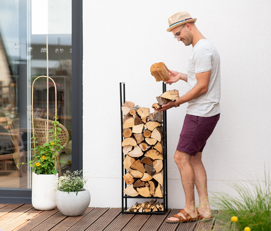 Mann schlichtet Holz in ein Stahl-Kaminholzregal »Porthos«.