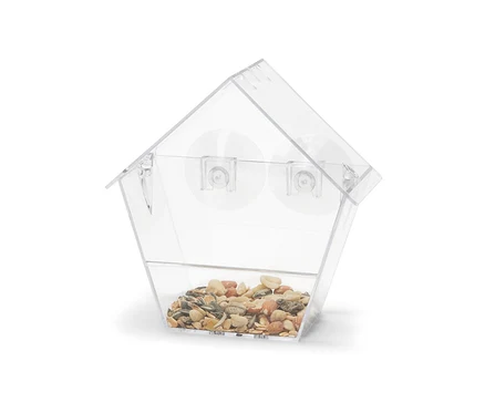 Ein transparentes Fenster-Vogelfutterhaus gefüllt mit Körnern.