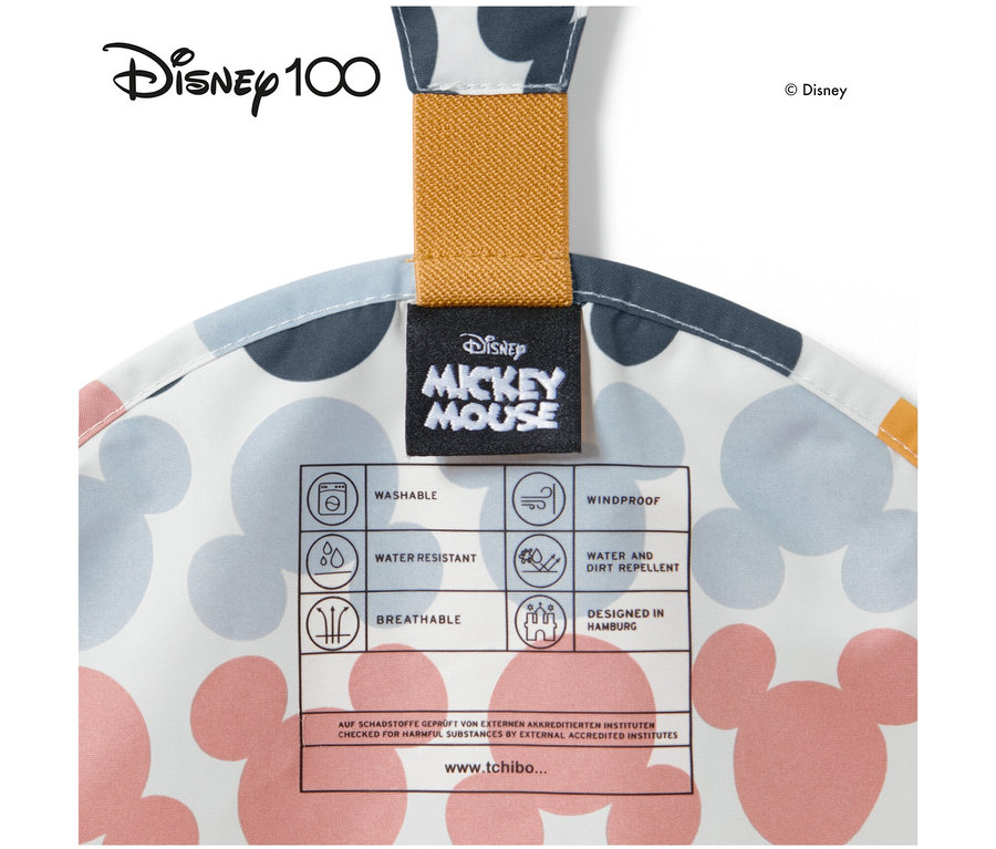 Detail einer Kleinkind-Thermo-Regenhose »Micky« mit Mickey Mouse-Muster, gelber Schlaufe und Etikett. Eigenschaften: Waschbar, wasserabweisend, atmungsaktiv, winddicht.