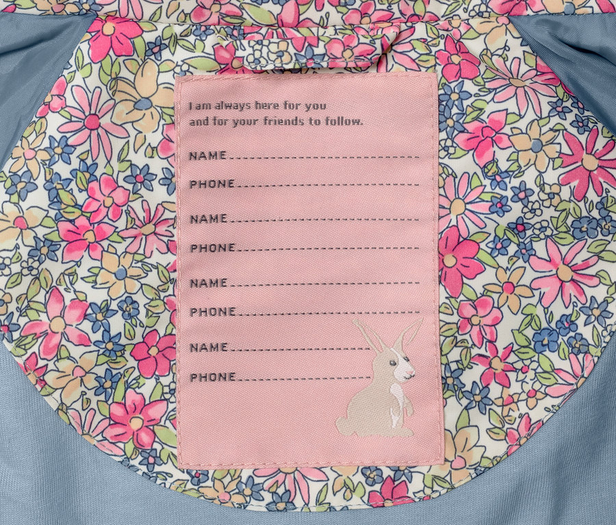 Innenansicht einer Kinder-Regenjacke mit Blumenmuster und Etikett für Name und Telefonnummer.