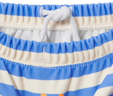 Detailaufnahme einer Baby-Schwimmwindel mit blau-weißen Streifen und orangefarbenem Aufdruck.