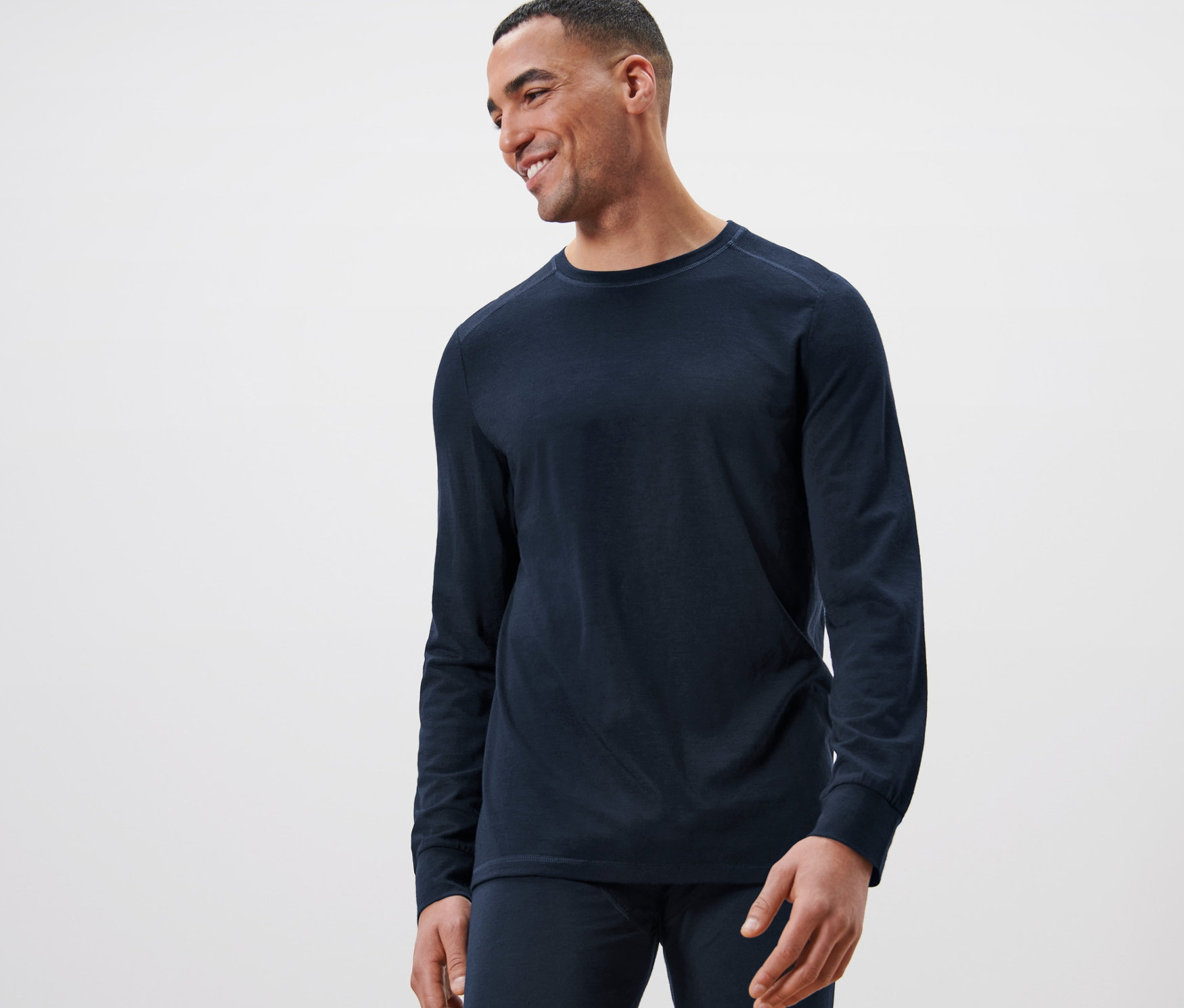 Mann lächelt und trägt ein marineblaues Langarmshirt mit RWS-zertifizierter Wolle.