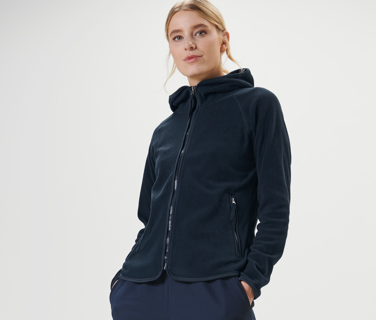 Frau posiert in dunkelblauer Kapuzen-Fleecejacke.