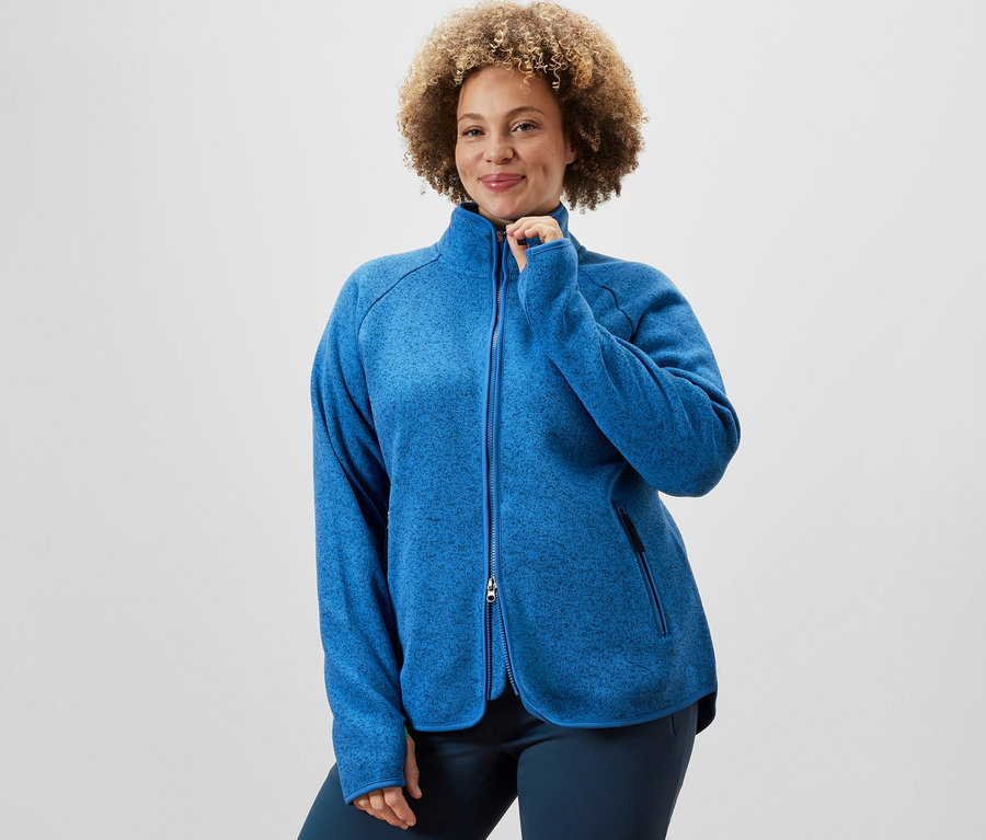 Frau schliesst blaue Strickfleece-Jacke und trägt Thermo-Jazzpants.