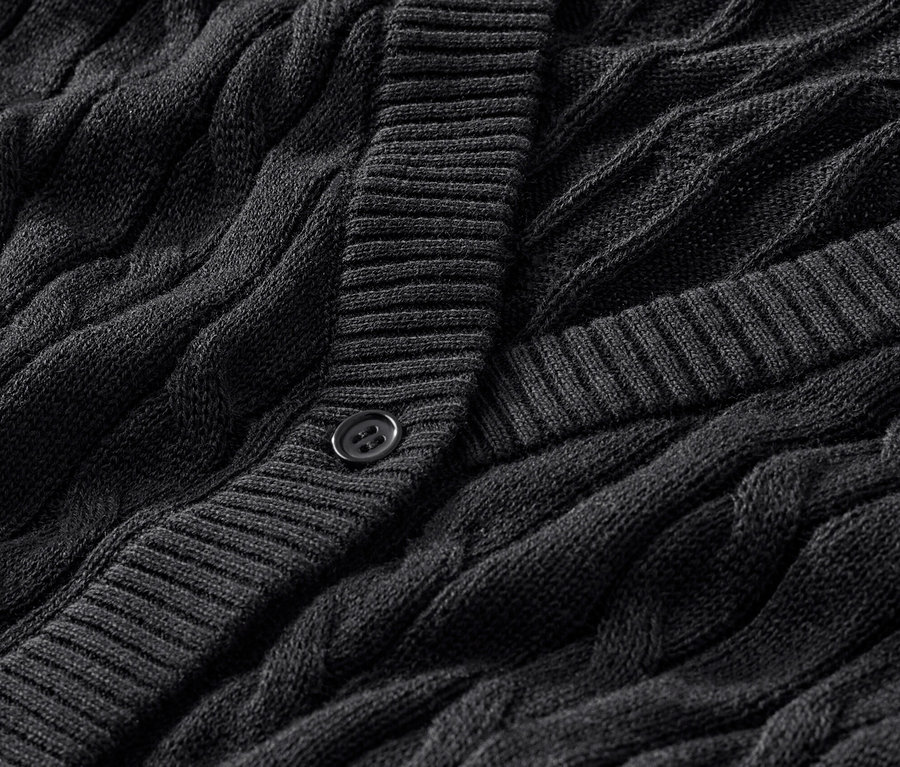 Detailaufnahme eines schwarzen Feinstrickcardigans mit Zopfmuster.