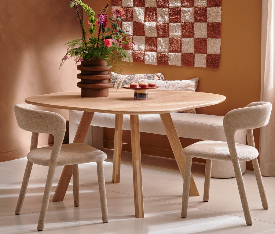 Zwei sandfarbene BePureHome Esszimmerstühle »Permit« an einem Holztisch mit Blumen.