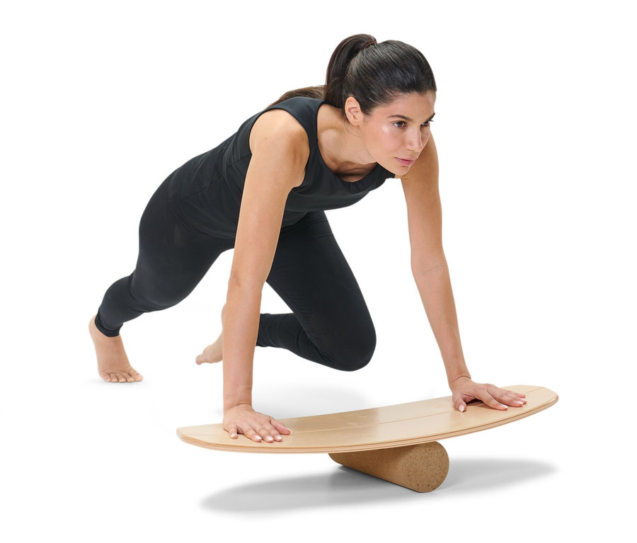 Frau in schwarzer Sportbekleidung macht Liegestütze auf einem Balance-Board.