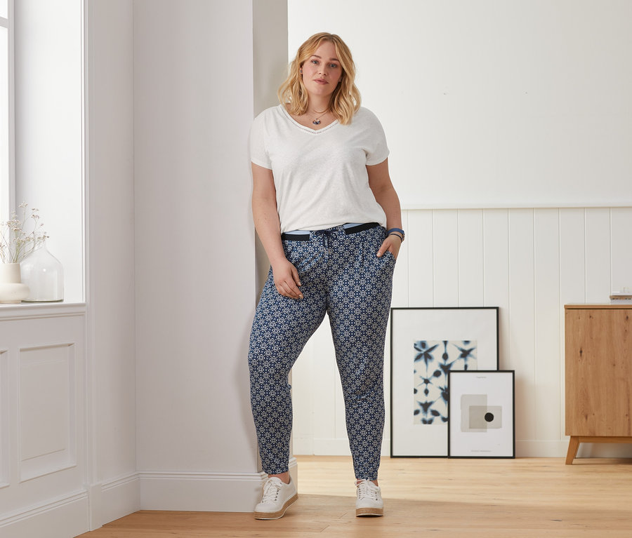 Frau posiert in weißem Shirt aus Leinenmix und Jerseyhose mit Alloverprint.