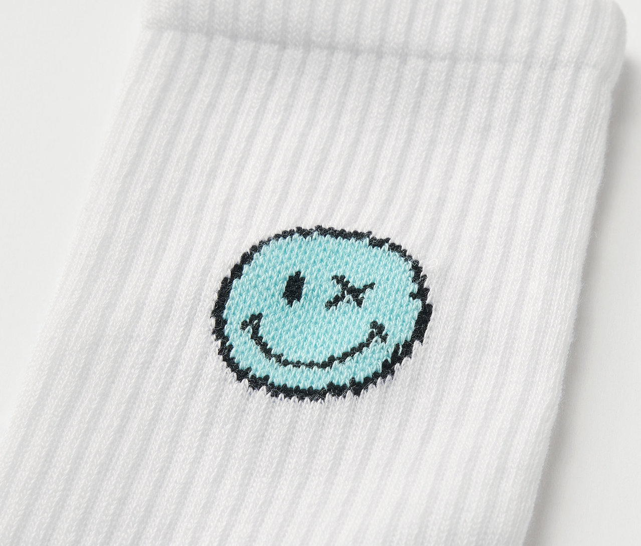 Detail einer weißen Kinder-Tennissocke SMILEYWORLD® mit blauem Smiley.