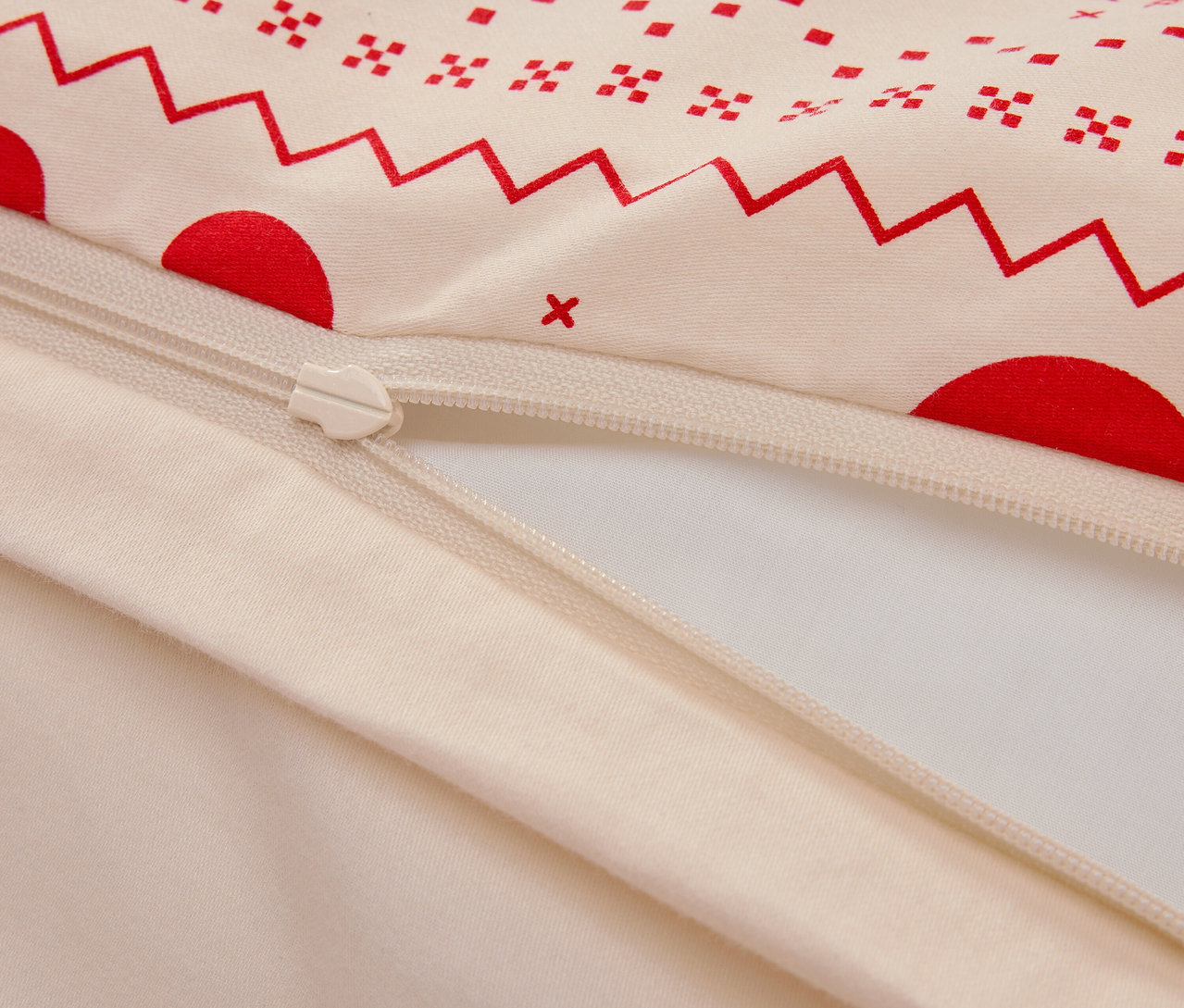 Detailansicht eines Baumwollbettbezugs mit rotem geometrischen Muster und Reißverschluss.