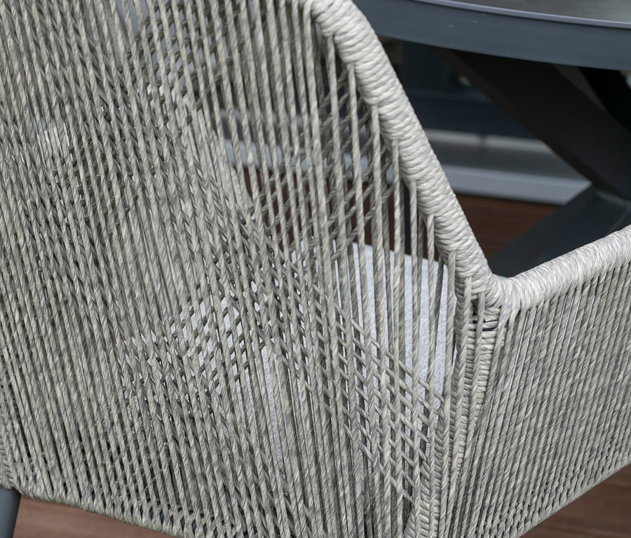 Detailansicht eines grauen deVries 2 Dining-Sessels aus Korbgeflecht an einem Tisch.