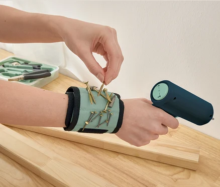 Eine Hand nimmt eine Schraube von einem Magnetarmband.