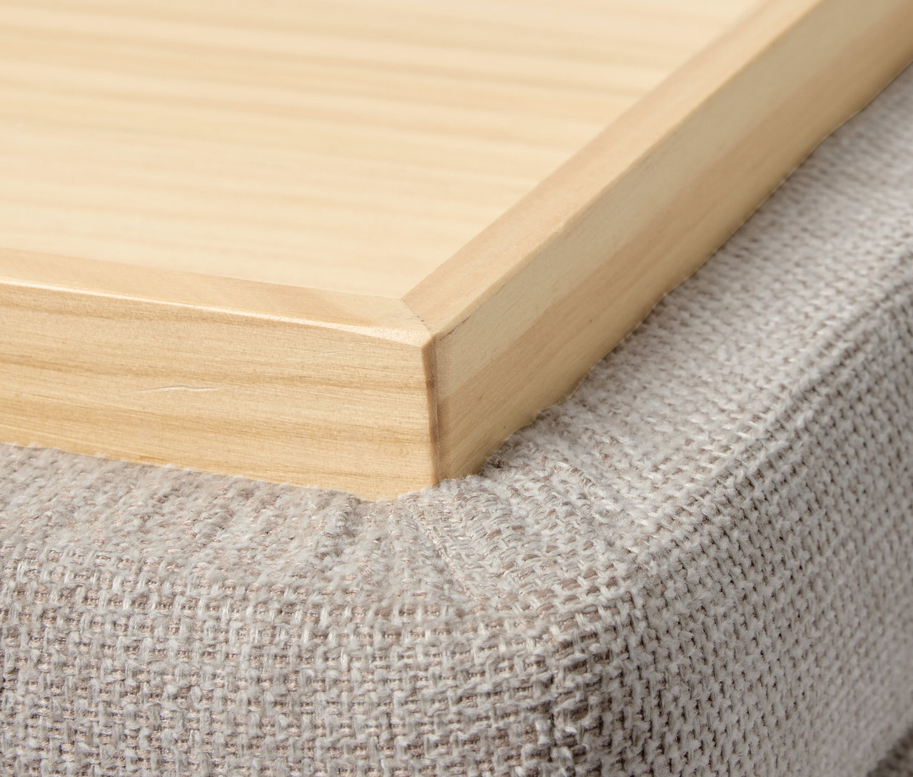 Detailaufnahme eines Holztabletts auf einem grauen Pouf. Pouf mit Rollen und Tablett