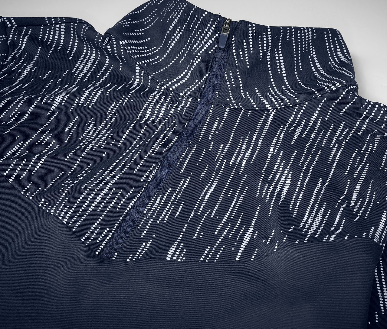 Detailaufnahme eines marineblauen Sportoberteils mit Reißverschluss und weißem Muster.