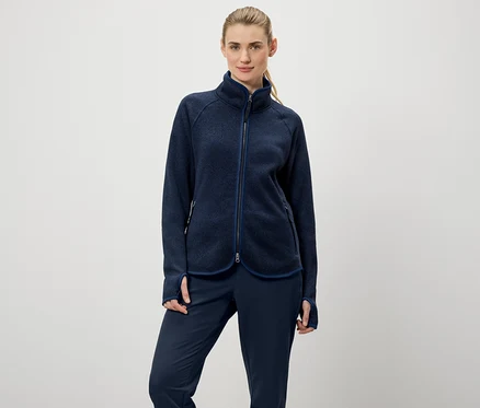 Frau trägt eine marineblaue Fleecejacke mit Reißverschluss und marineblaue Hosen.