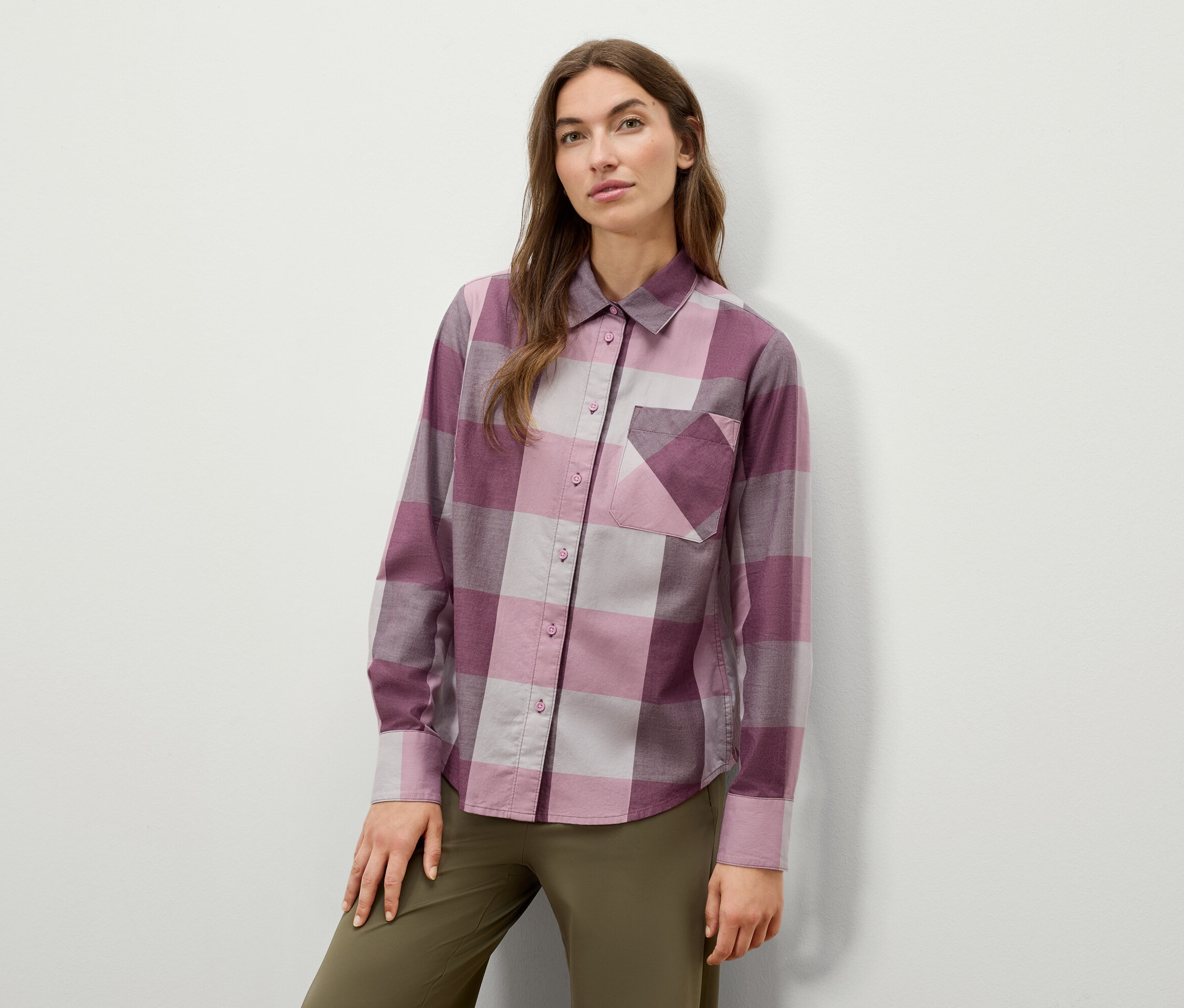 Frau posiert in einem karierten Langarmhemd und olivgrünen Hosen.
