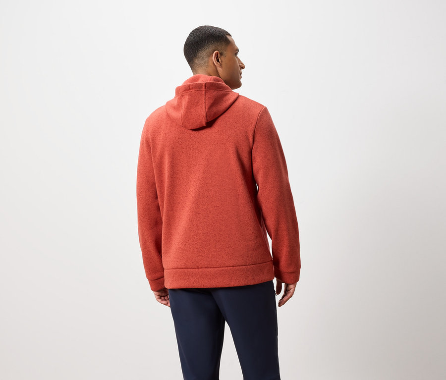 Ein Mann mit dem Rücken zur Kamera trägt einen orangefarbenen Hoodie und dunkelblaue Hosen.