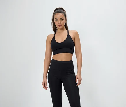 Frau posiert in einem schwarzen Sport-BH und Leggings.