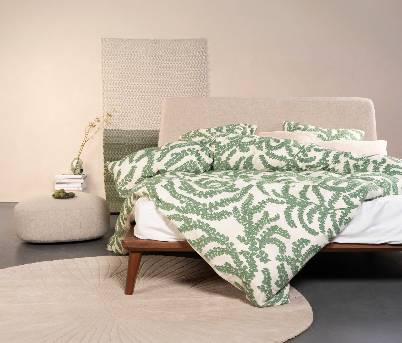 Bett mit Essenza Satin-Bettwäsche »Eleria« in Normal- und Übergröße mit grünem Blätterdruck, dazu Teppich, Hocker und Deko.