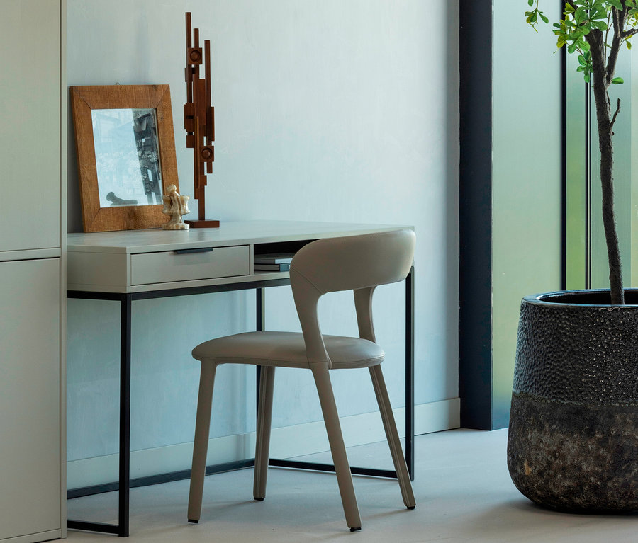 Abbildung eines WOOOD Schreibtischs »Nore« mit Stuhl, einer Skulptur und einem Bilderrahmen auf dem Tisch.
