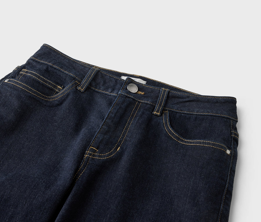 Nahaufnahme einer dunkelblauen Jeans mit gelben Nähten, Knopf und Taschen auf hellem Hintergrund.