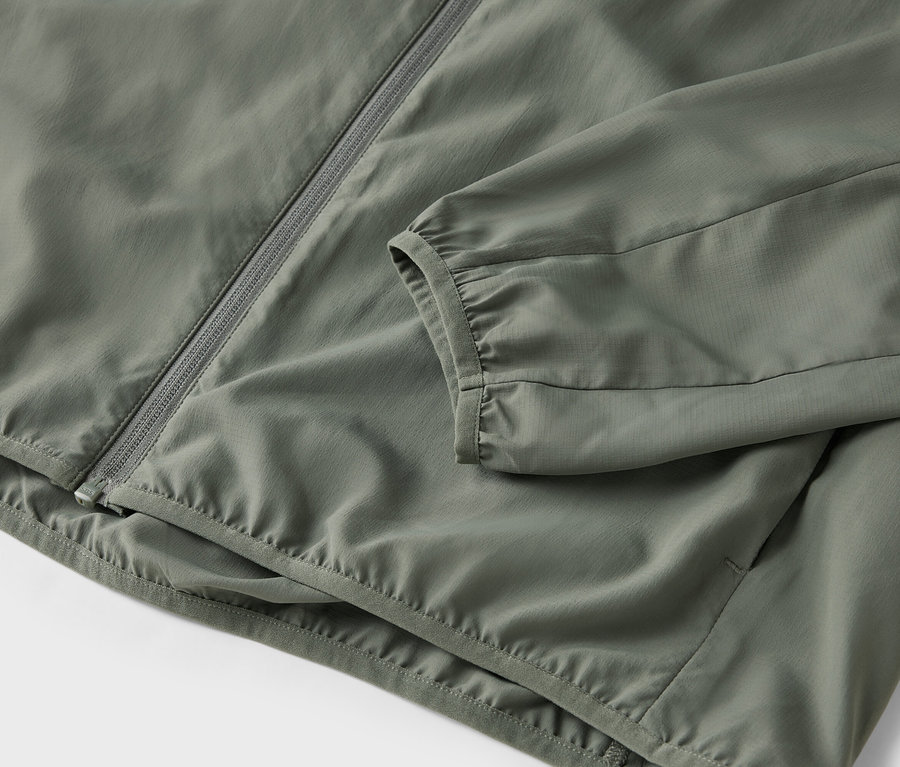 Nahaufnahme einer olivgrünen Jacke mit Reißverschluss.