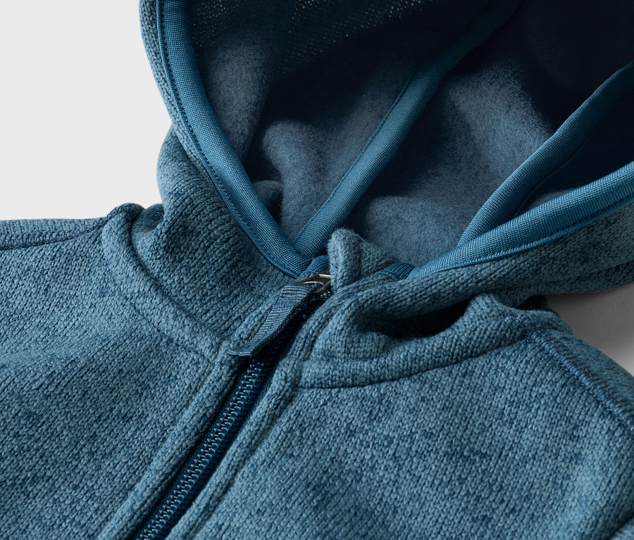 Nahaufnahme einer blaugrünen Fleecejacke mit Kapuze und Reißverschluss.