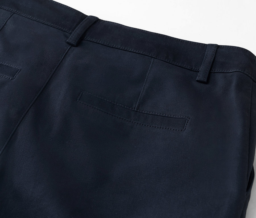 Detailansicht der Rückseite einer marineblauen Hose mit Gesäßtasche.