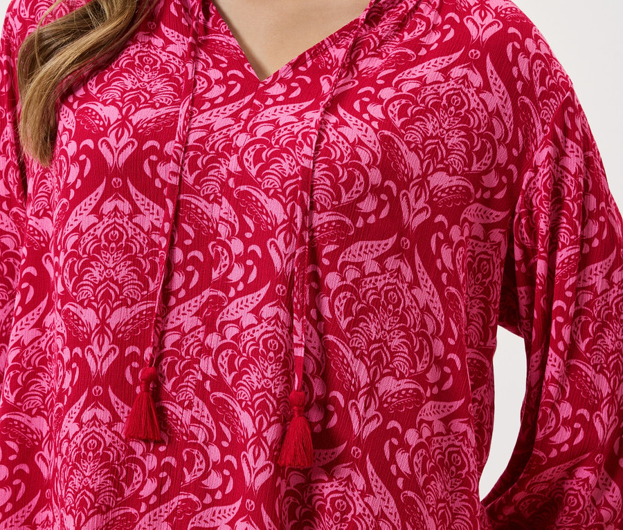 Nahaufnahme eines roten Oberteils mit rosa Blumenmuster und Kordelzug.